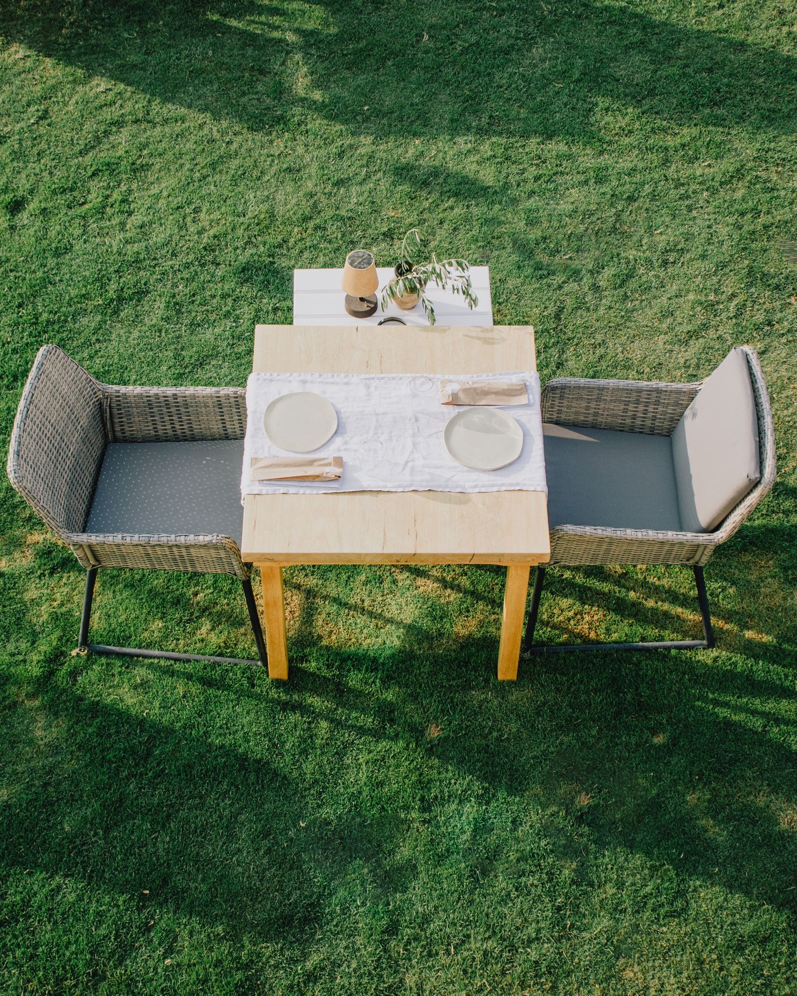 Overhead shot of a small two-seat outdoor table set for a meal on a grass lawn